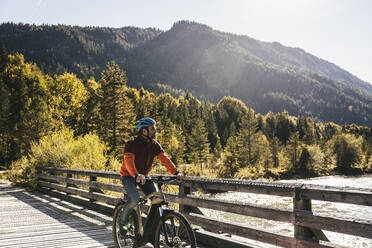 Mann mit Helm beim Mountainbiking auf einer Brücke - UUF25034