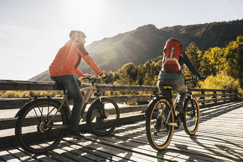 Couple riding bicycles at bridge on sunny day - UUF25046