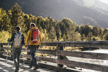 Mature couple with backpacks hiking on sunny day - UUF25058