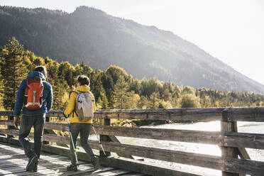 Hikers with backpacks walking on bridge - UUF25064