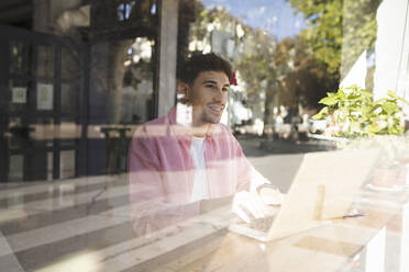 Thoughtful businessman looking out of cafe window - JCCMF04457