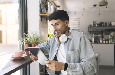 Young businessman using tablet PC in coffee shop - JCCMF04458