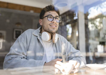 Thoughtful businessman looking out of cafe window - JCCMF04466