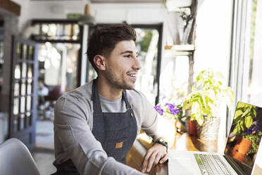 Geschäftsmann mit Laptop auf dem Tisch und Blick aus dem Fenster - JCCMF04479