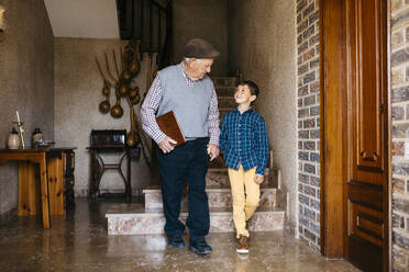 Grandson holding grandfather hand at home - JRFF05201