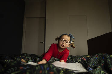 Nettes Mädchen mit Brille liest Buch auf dem Bett - SSGF00210