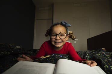 Glückliches Mädchen mit Buch auf dem Bett liegend - SSGF00211