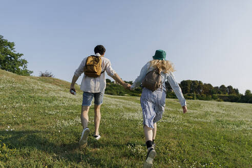 Couple with backpacks running on meadow - TYF00011