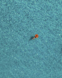 Luftaufnahme eines schwimmenden Mädchens mit einem roten Donut, Ghadira Bay, Malta. - AAEF13173