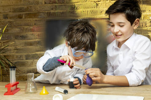 UK, Jungen (4-5, 10-11) machen wissenschaftliche Experimente zu Hause - ISF25326