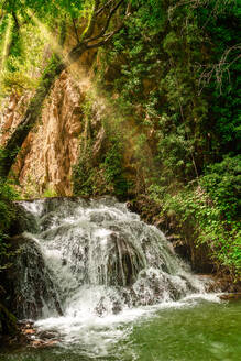 Seitenansicht des Wasserfalls unter den Bäumen an einem sonnigen Tag - ADSF31472