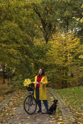 Woman standing with bicycle and dog at public park - SSGF00228