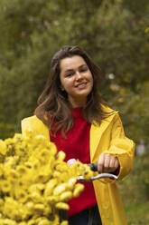 Lächelnde Frau mit Blumen auf dem Fahrrad - SSGF00229
