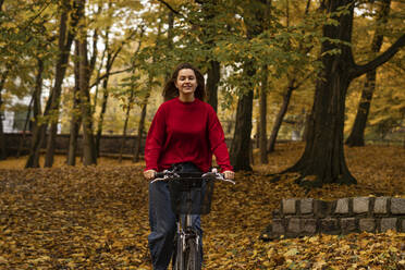 Lächelnde Frau beim Radfahren im Herbstpark - SSGF00232