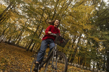 Lächelnde Frau beim Radfahren im herbstlichen Park - SSGF00233