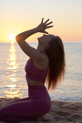 Young female athlete practicing yoga at beach - VEGF05141