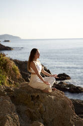 Female athlete practicing lotus position on rock - VEGF05153