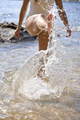 Young woman splashing water at beach - VEGF05165