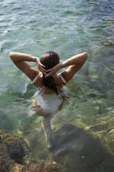 Woman with hands in hair at sea - VEGF05169