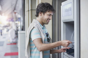 Smiling man putting credit card in ATM - RORF02870