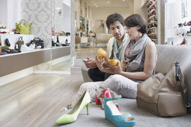 Freundin und Freund betrachten Sandale beim Einkaufen im Schuhgeschäft - RORF02883