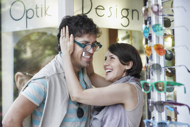 Happy woman trying eyeglasses on boyfriend at store - RORF02885