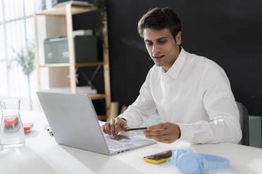 Geschäftsmann mit Kreditkarte beim Online-Shopping mit Laptop im Büro - GIOF14042