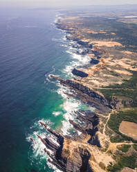 Luftaufnahme der sich an den Klippen des Cabo de Farol Sardao brechenden Wellen mit Blick auf den Atlantischen Ozean in Vila Nova de Milfontes, Region Alentejo, Portugal. - AAEF13298