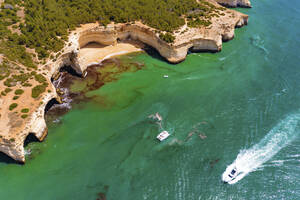 Luftaufnahme eines Bootes, eines Katamarans und einer Yacht, die auf dem Meer in der Nähe der Klippen des Strandes Praia da Corredoura in Lagoa, Algarve, Portugal, kreuzen. - AAEF13311