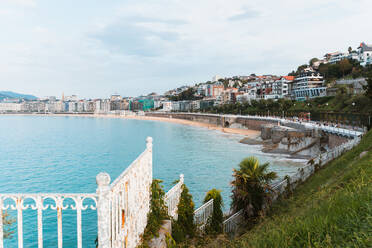 Malerische Landschaft von ruhigen blauen Wasser des Golfs von Biskaya waschen Ufer mit Gehweg und Wohngebäuden in San Sebastian in Spanien unter bewölktem blauen Himmel im Tageslicht - ADSF31537