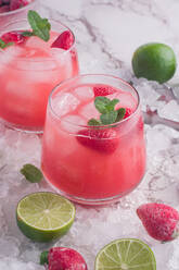 Von oben Gläser mit kaltem Kokosnusswasser mit Erdbeeren auf Eis serviert Hintergrund - ADSF31542
