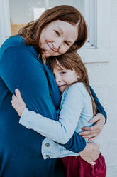 Grandma and young grand daughter hugging in a loving embrace - CAVF95062