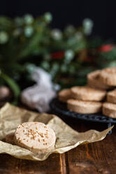 Stapel von appetitlichen süßen Butterkeksen mit Haselnüssen serviert auf Teller auf Holztisch mit festlichen Geschenkpapier und Bänder für Weihnachten Feier - ADSF31610