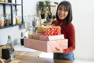 Glückliche Geschäftsfrau trägt Geschenkkartons nach Hause - GIOF14067