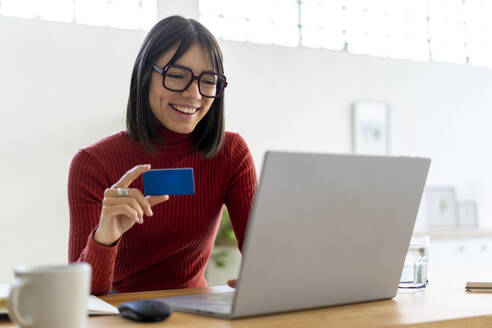 Glückliche berufstätige Frau bei der Online-Zahlung per Kreditkarte - GIOF14084