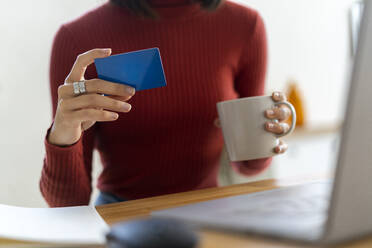 Geschäftsfrau mit Tasse und Kreditkarte im Home Office - GIOF14086