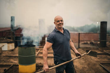 Smiling worker standing with tool at coal factory - GRCF01050