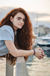 Porträt einer jungen rothaarigen Frau in einem Hafen einer Stadt - CAVF95075