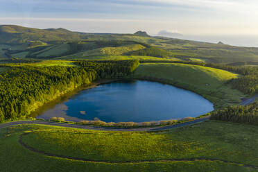 Luftaufnahme des Lagoa da Lomba, eines kleinen, von Vegetation umgebenen Sees bei Sonnenuntergang auf der Ilha das Flores, Azoreninseln, Portugal. - AAEF13339