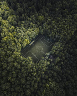 Aerial view of a football field with people playing soccer surrounded by forest trees in Moscow city, Russia. - AAEF13399