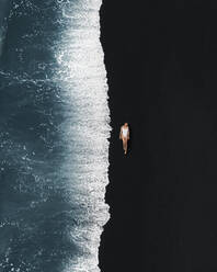 Luftaufnahme eines Mädchens am schwarzen Sandstrand von El Golfo, Lanzarote, Spanien. - AAEF13435