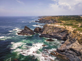 Aerial view of rough sea waves along the coastline in Odeceixe, Faro, Portugal. - AAEF13454