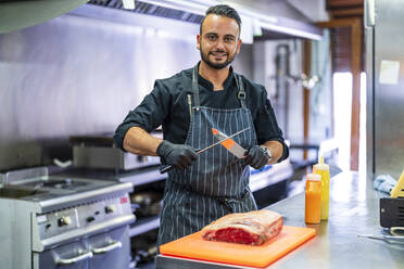 Küchenchef schärft Messer zum Schneiden von Fleisch in Großküchen - DLTSF02368