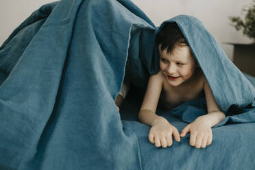 Lächelnder Sohn sieht seine Mutter an, die sich unter einer Decke im neuen Haus versteckt - SEAF00005