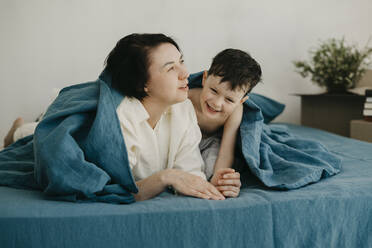 Cheerful son playing with mother on bed at new home - SEAF00007