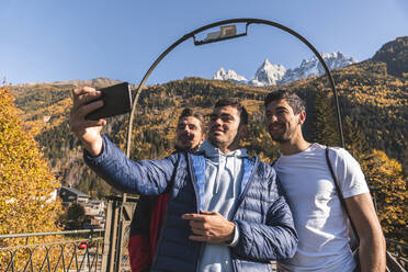 Mann macht Selfie mit Wanderfreunden durch Smartphone an sonnigem Tag, Chamonix, Frankreich - JAQF00877