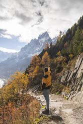 Junger Mann steht vor der Aiguille des Grands Charmoz an einem sonnigen Tag, Chamonix, Frankreich - JAQF00895