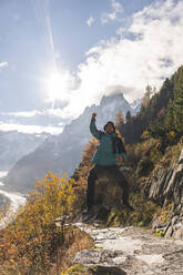 Excited man jumping in front of Aiguille des Grands Charmoz on sunny day, Chamonix, France - JAQF00898