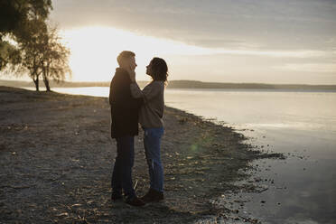 Romantic couple standing at lakeshore - LLUF00311