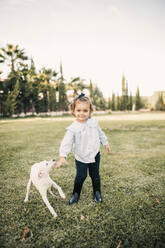 Smiling girl with dog standing at ranch - GRCF01087